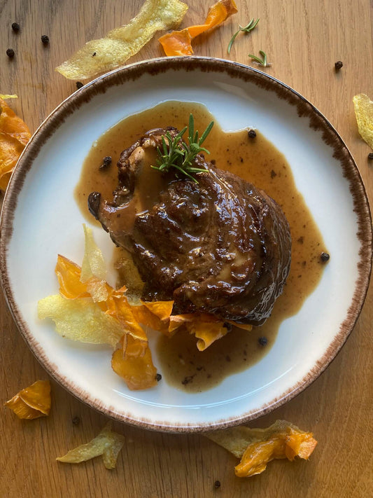 Carrillera de cerdo con patatas servido en su salsa sobre un plato blanco