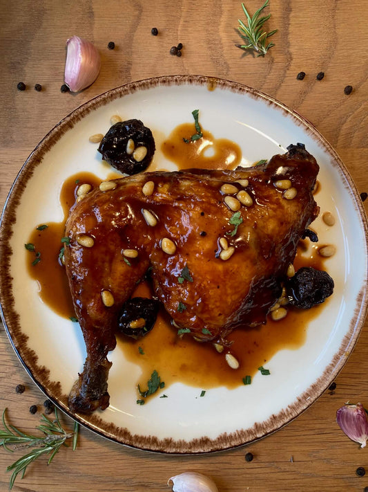 Pollo asado con ciruelas y piñones servido en un plato blanco