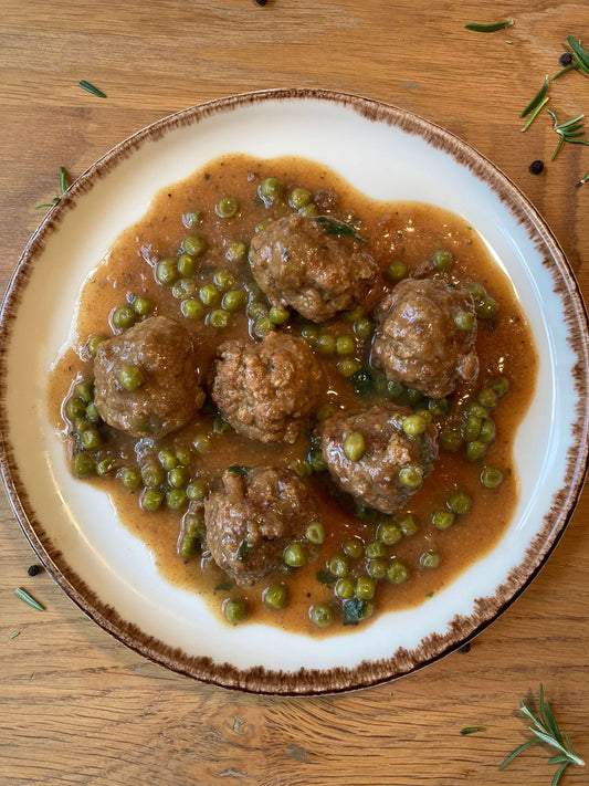 Plato de Albondigas caseras con guisantes en su salsa servidas en un plato blanco