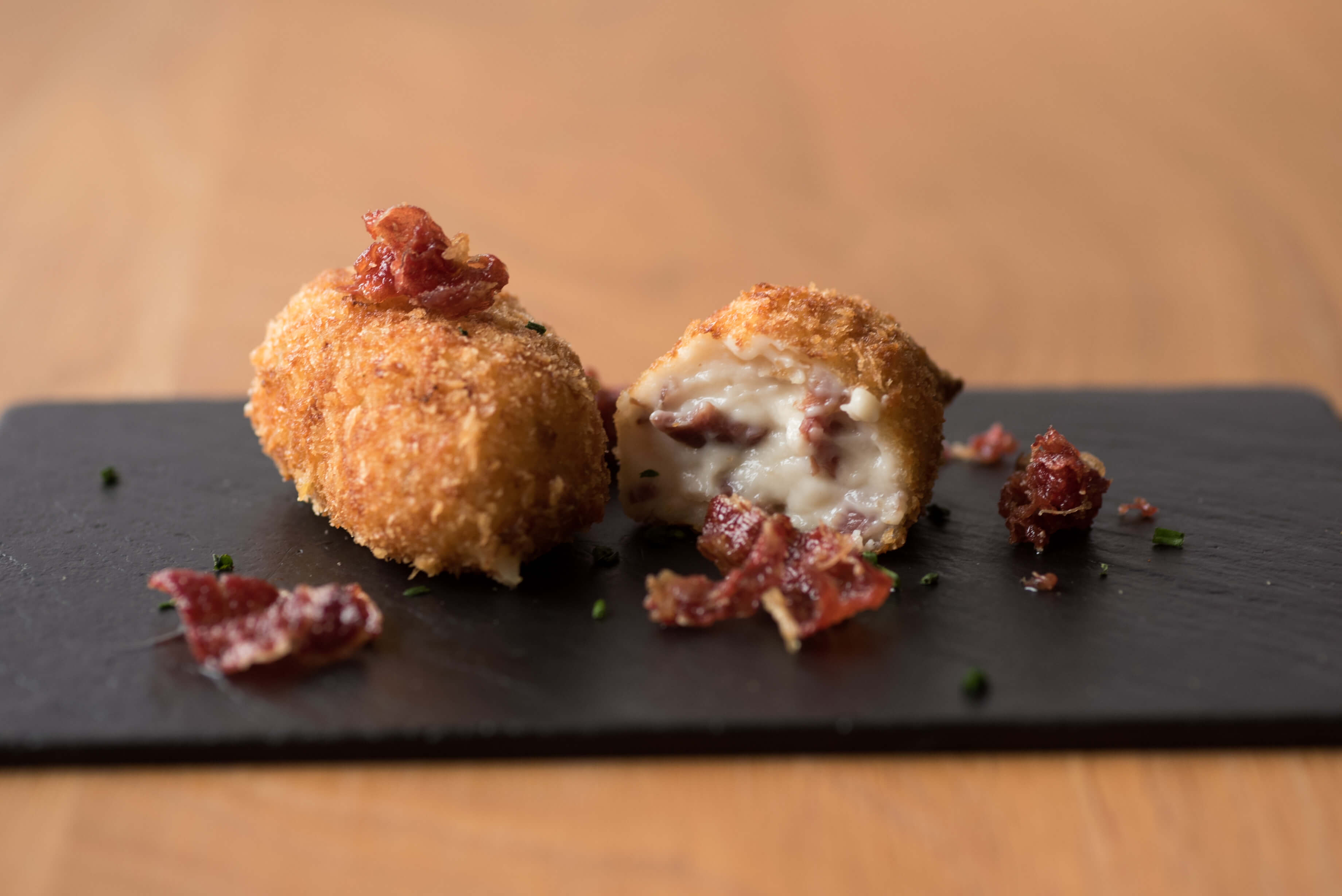 Croquetas artesanas de jamón ibérico abiertas con relleno de bechamel y trozos de jamón por encima